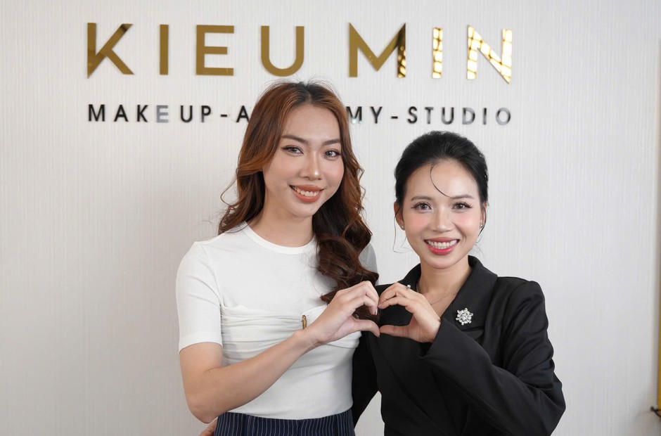 Hai học viên tạo dấu hình trái tim trước bảng hiệu studio Kiều Min