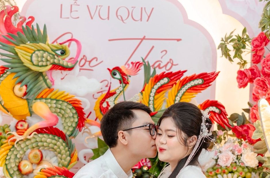Cô dâu và chú rể mặc áo dài trong lễ vu quy trước phông rồng phượng