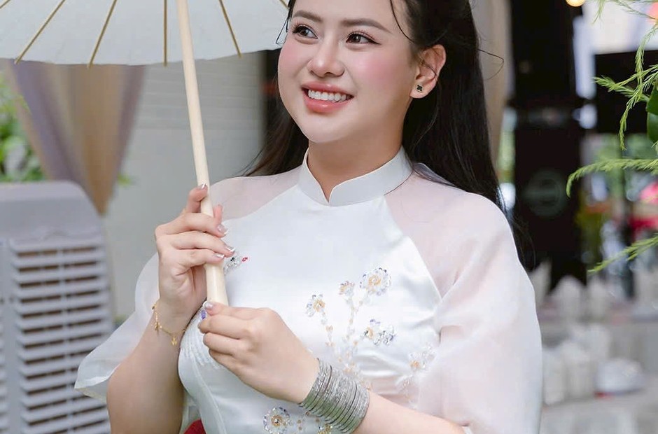 Cô dâu mặc áo dài trắng thêu hoa, cầm chiếc ô giấy trắng