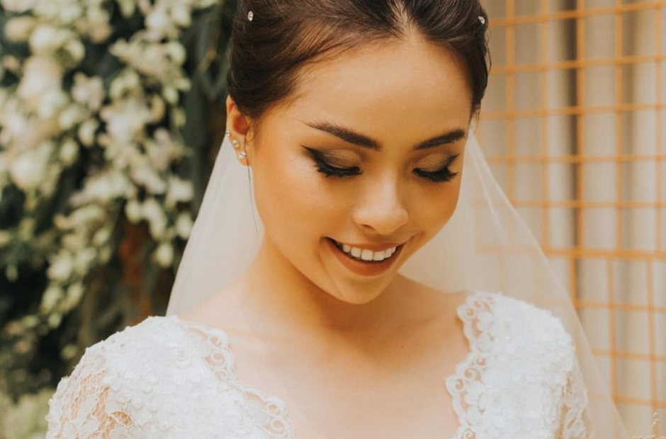 Cô dâu váy ren trang điểm mắt đậm, nhìn xuống bó hoa