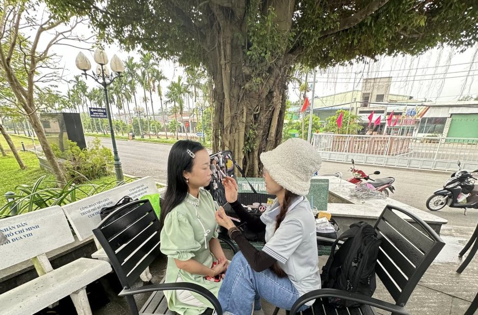 Thợ trang điểm cho khách ngoài trời dưới tán cây