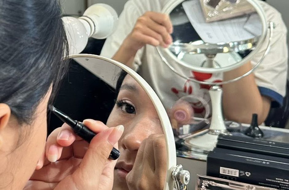 Tự trang điểm mắt với gương nhỏ trên bàn
