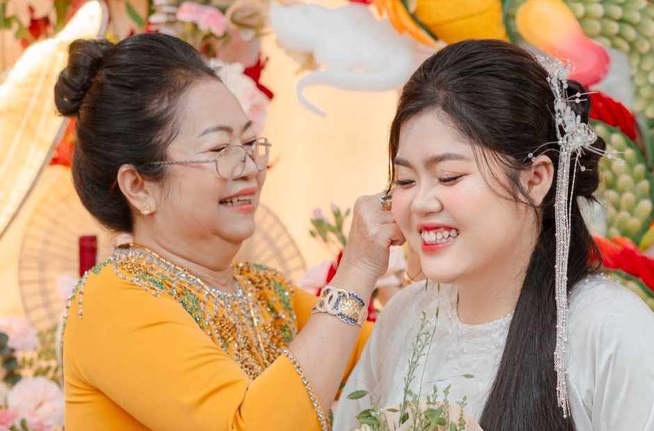 Mẹ cô dâu áo dài vàng chỉnh tóc cho cô dâu trong lễ vu quy