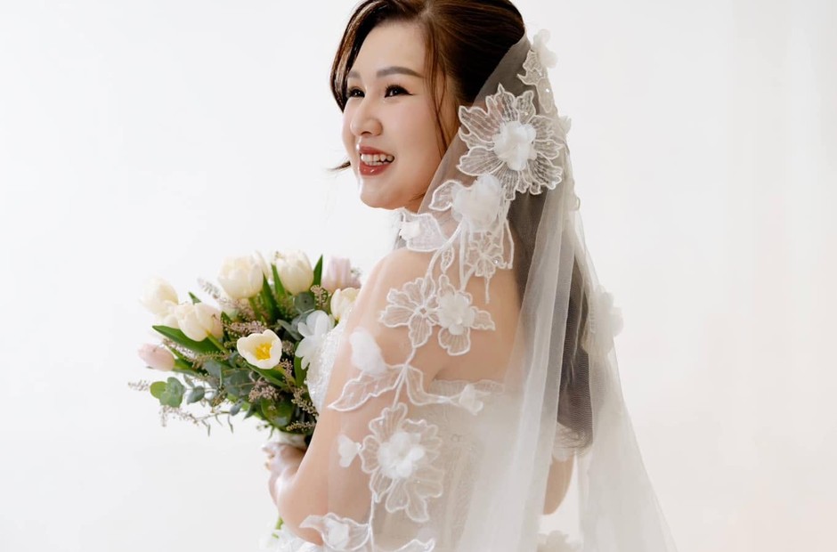 Cô dâu cầm hoa, tóc búi nhẹ và voan mềm