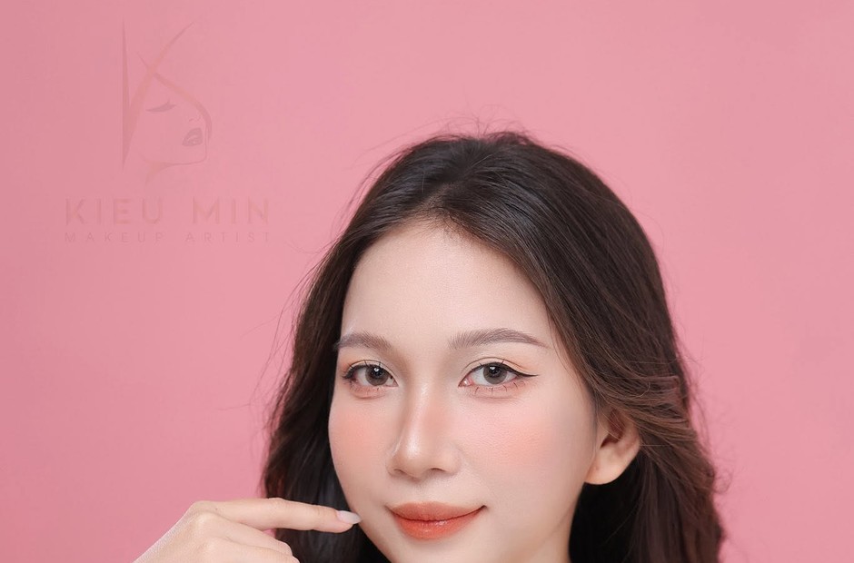 Khách nữ tóc đen xõa, nền da mỏng và môi cam nhạt trước phông hồng