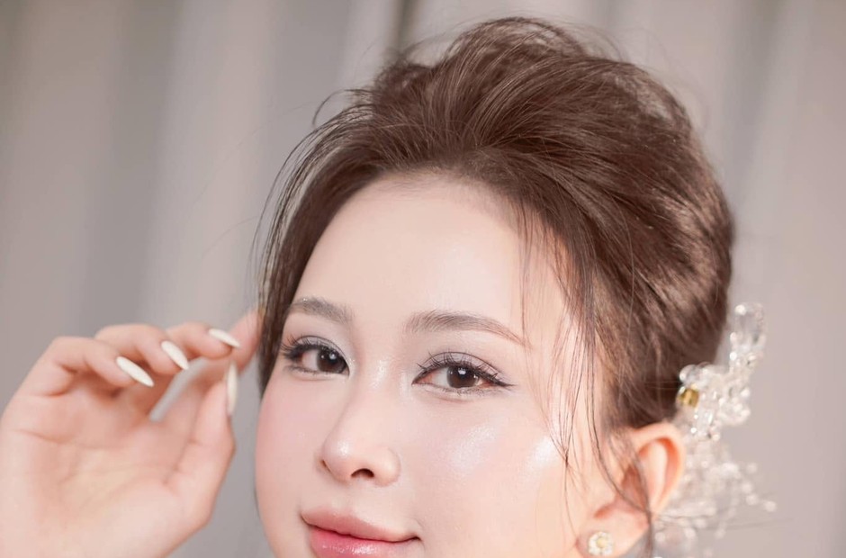 Cô dâu tóc búi cao, má hồng nhẹ, cài hoa nhỏ