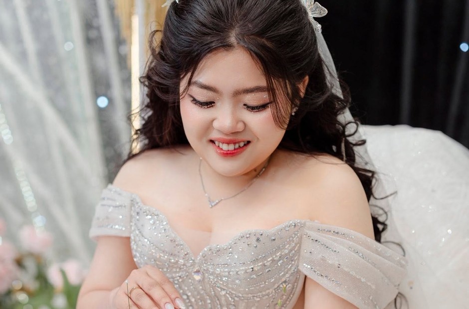 Cô dâu tóc búi thấp cười nhẹ trong váy cưới