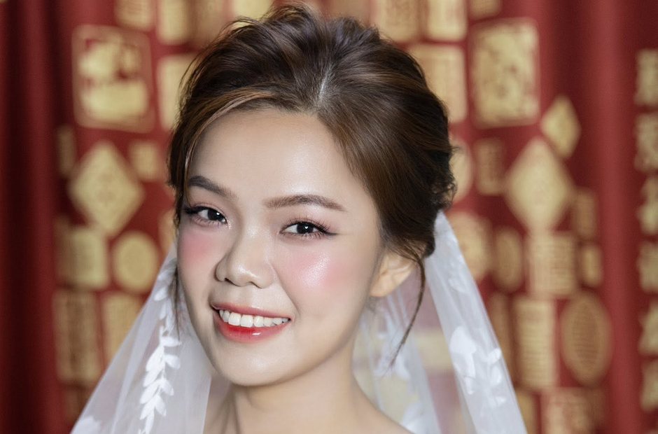 Cận cảnh gương mặt cô dâu với môi đỏ và má hồng nhạt trên phông cưới đỏ