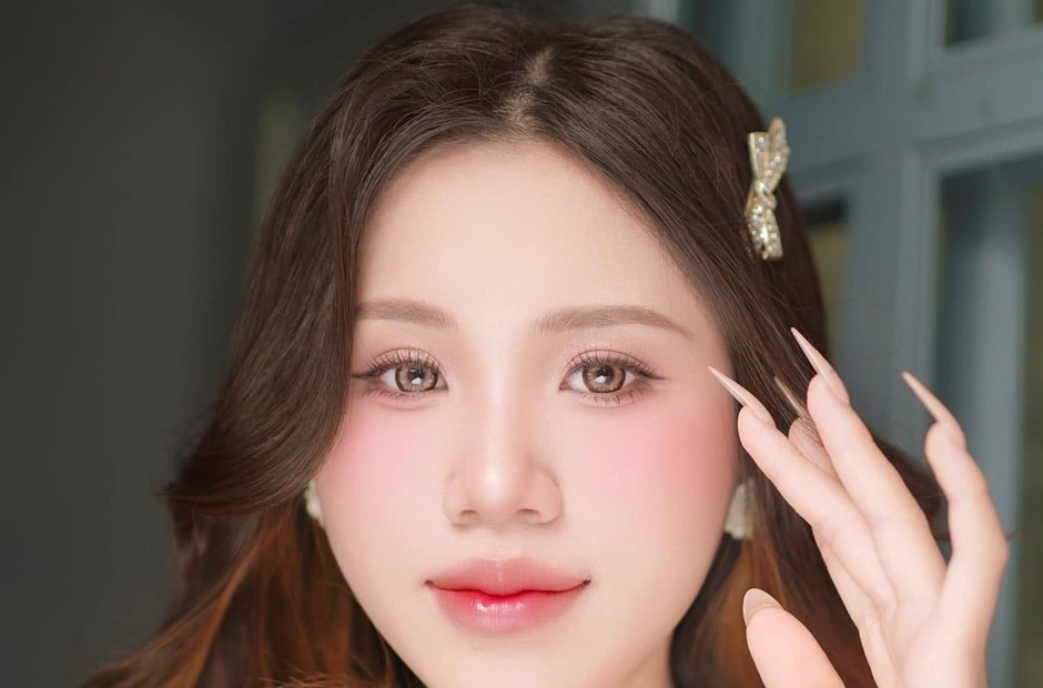 Khách nữ tóc nâu xõa cài kẹp nơ nhỏ, môi hồng bóng và má hồng nhẹ
