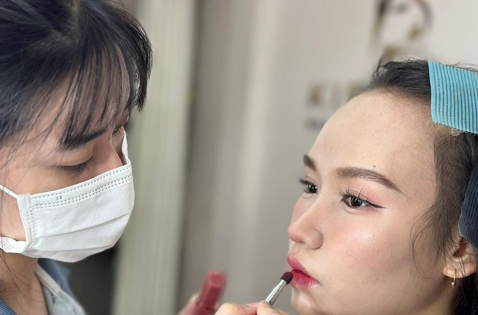 Thợ trang điểm đang tô son cho khách trong buổi làm việc
