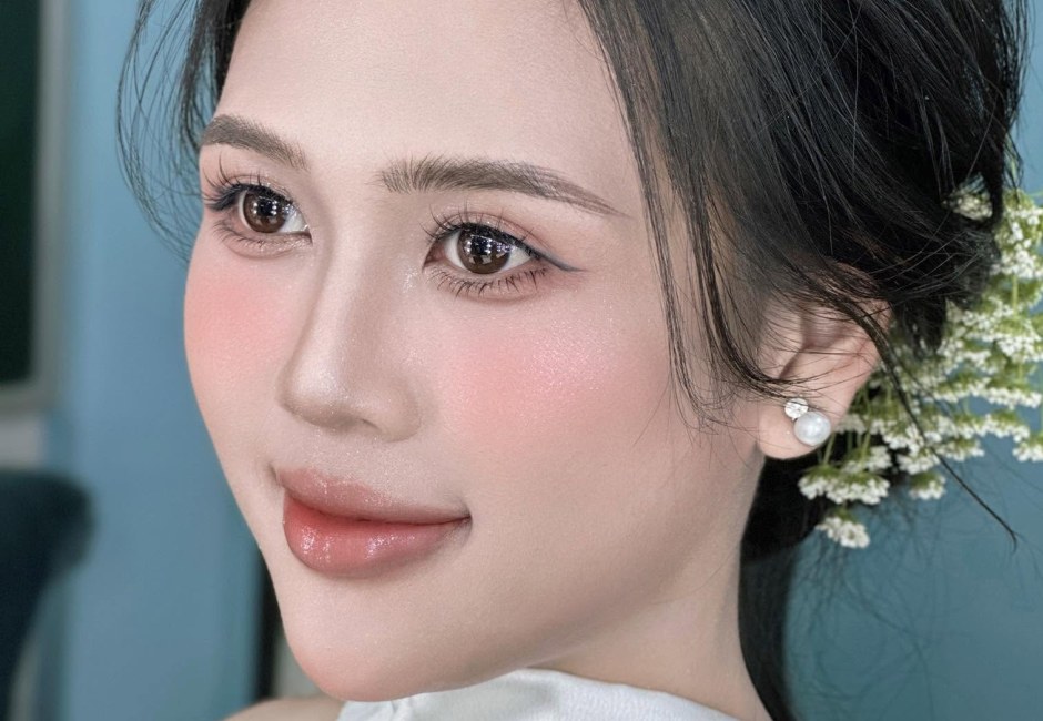 Khách nữ trang điểm tông hồng nhẹ đi tiệc, tóc búi cài hoa